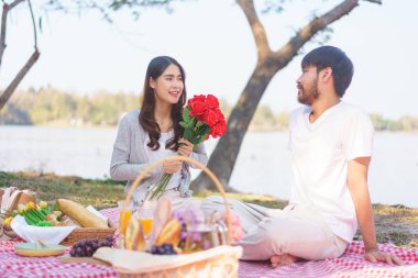 Sevgilisinden kırmızı gül buketi tutan genç bir kadın. Mutlulukla ve gözünün içine bakarak..