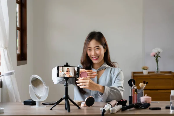 stock image Beauty blogger reviewing blush on product while recording video on smartphone for makeup vlogger.