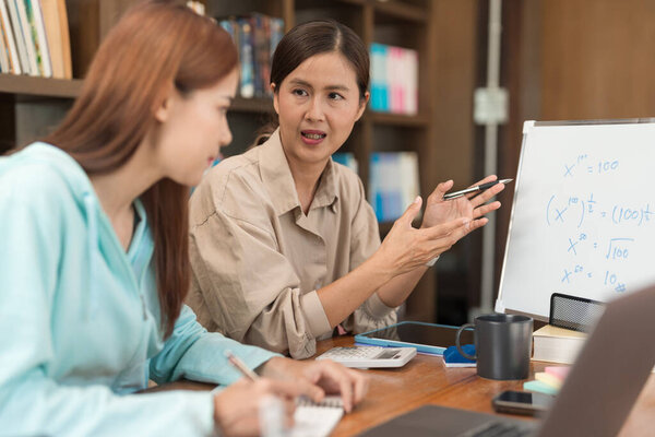 College education concept, Female tutor explaining math equations on whiteboard to student.