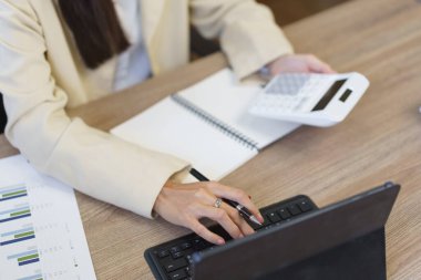 Sekreter konsepti, kadın sekreter tablet üzerindeki verileri hesaplamak ve yazmak için hesap makinesi kullanıyor.
