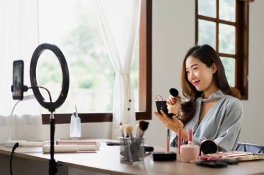 Güzellik blogcusu makyaj vlog kaydedicisinde kozmetik incelemesi için ürünleri uygularken allık sürerek fırça kullanır.