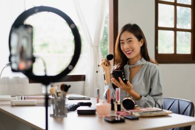 Güzellik blogcusu makyaj vlog kaydedicisinde kozmetik incelemesi için ürünleri uygularken allık sürerek fırça kullanır.