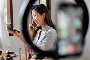 Makyaj vlog kaydedicisinde kozmetik incelemesi için tozu fırçayla kullanan güzellik blogcusu.