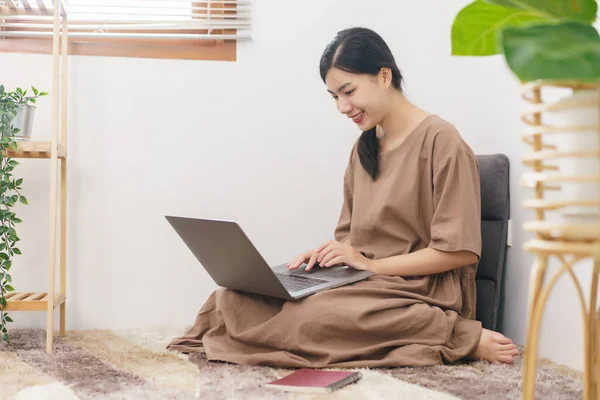 stock image Relaxation lifestyle concept, Young Asian woman use laptop for entertainment in living room at home.