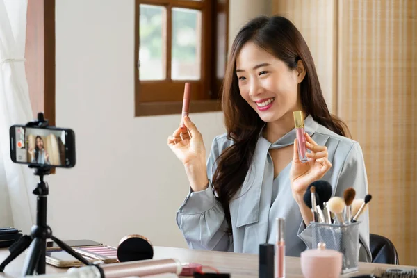 stock image Beauty blogger reviewing lipstick product while recording video on smartphone for makeup vlogger.