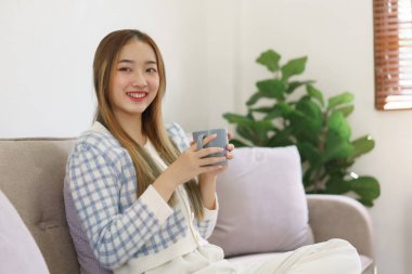 Boş zaman konsepti, elinde kahve fincanı olan ve rahatlamak için kanepede oturan kadınlar..