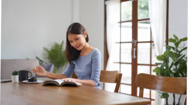 Work from home concept, Business women eats dessert and reads book to relax after working at home.