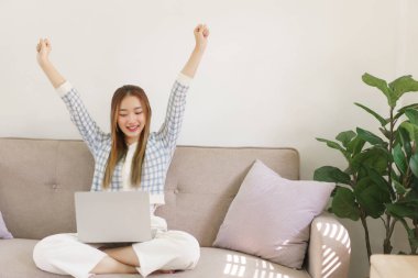 Dinlenme zamanı konsepti, kadınlar kanepede oturup dizüstü bilgisayarda çalışıyor ve başarı jestleri yapıyor..