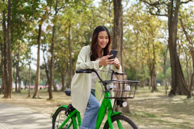 Kadınlar parkta egzersiz yaptıktan sonra sohbet etmek ve sosyal medyada sörf yapmak için akıllı telefon kullanıyorlar..