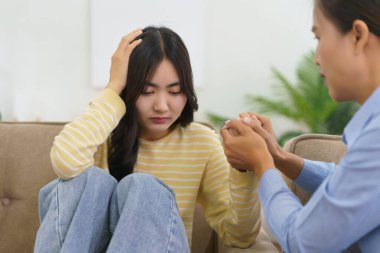 Kadın psikolog, depresyon geçiren hastayı rahatlatmak ve cesaretlendirmek için el ele tutuşuyor..