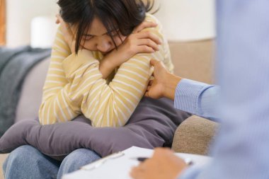 Klinikte seans terapisi görürken kadın psikolog konuşuyor ve depresyondaki hastayı rahatlatıyor..