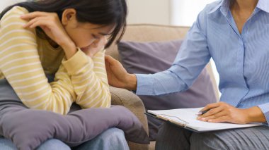 Klinikte seans terapisi görürken kadın psikolog konuşuyor ve depresyondaki hastayı rahatlatıyor..