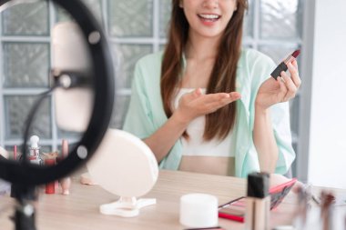 Beauty Vlogger konsepti, Vlog için ürün ve kayıt videosu sunmak için ruj tutan genç kadın..