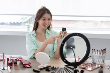 Beauty blogger concept, Young woman point on liquid foundation bottle to introduce product on Vlog.