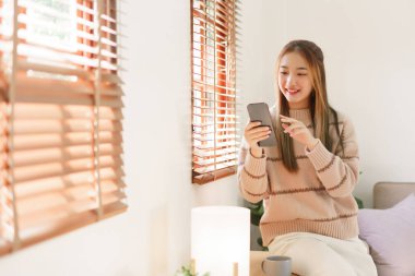 Dinlenme zamanı kavramı, kadınlar pencerenin yanında otururken sosyal medyada akıllı telefon kullanıyor..