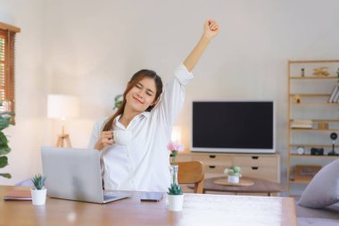 Relaxing time concept, Woman drinks coffee and arms stretching after tired of work at home office.