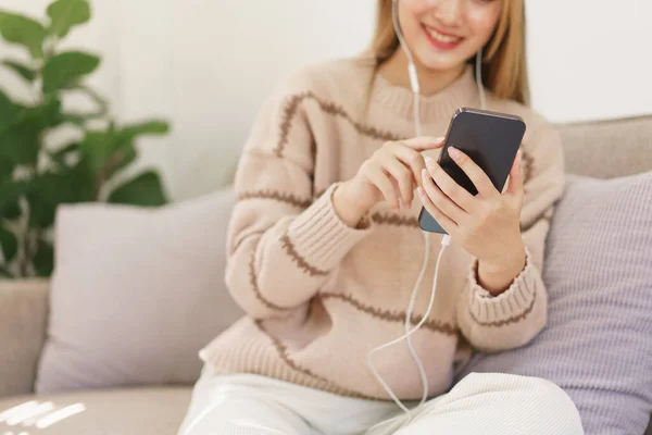 休息时间的概念 女人们戴耳机浏览社交媒体 在智能手机上听音乐 — 图库照片