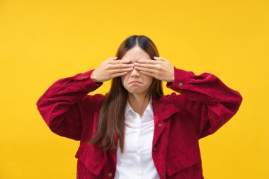 Kadınlar gözlerini kapatmak için ellerini kullanırken izole edilmiş sarı arka planda üzüntü hissediyorlar..