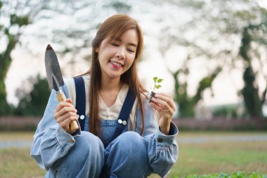 Genç kadın mala ve sebze fidelerini evin önündeki sebze bahçesinde yetiştirmek için tutuyor..