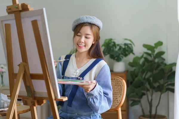 若い女性アーティストは パレット上の色をミックスし 自宅のスタジオで楽しんでキャンバス上の絵画作品に — ストック写真