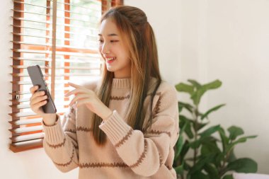 Boş zaman kavramı, kadınların pencere kenarında otururken sosyal medyada akıllı telefon kullanması..