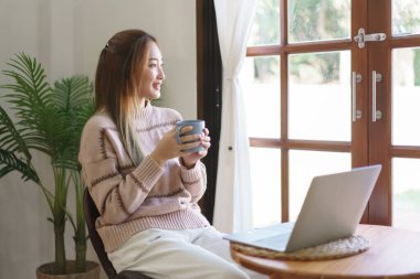 Dinlenme zamanı konsepti, kadınlar laptopta çalışırken kahve içip dışarı bakıyorlar..