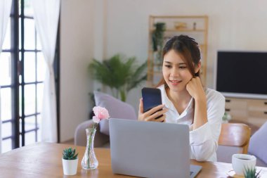 Rahatlatıcı zaman kavramı, modern ev ofisinde çalışan kadınlar akıllı telefondan video kullanıyor..
