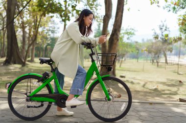Kadınlar parkta egzersiz yaptıktan sonra sohbet etmek ve sosyal medyada sörf yapmak için akıllı telefon kullanıyorlar..