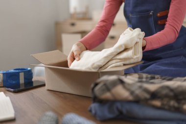 Online business concept, Women entrepreneur packing clothes product in box for delivery to customer.
