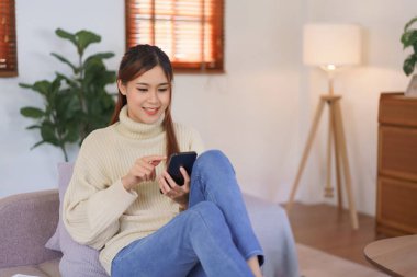 Rahatlatıcı zaman konsepti, kadınlar modern ev ofisteki akıllı telefondan online alışverişe kanepede oturur..