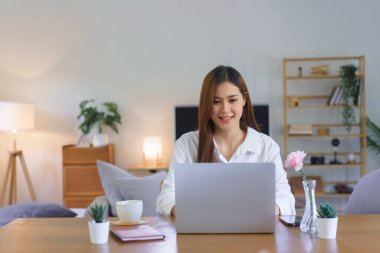 Ev kavramında çalışan kadınlar, modern ev ofisinin başlangıcında çalışırken dizüstü bilgisayarda yazı yazıyorlar.