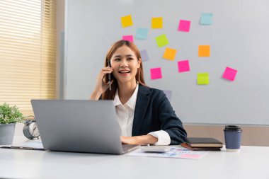 Concept of modern girl leadership, Businesswoman talking on smartphone as looking at data on laptop.