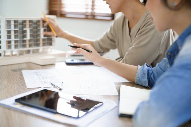 Mühendislik konsepti, iki kadın mühendis bina modelini gösteriyor ve tartışıyor..