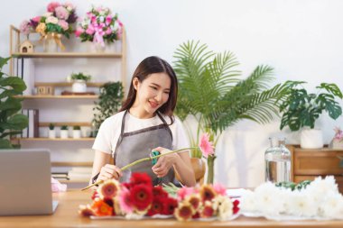 Çiçekçi konsepti, Gerbera 'yı makasla kesen kadın çiçekçi dükkanda vazo yapmaya hazırlanıyor..