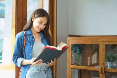 Education and literacy concept, College student girl smiling and standing to reading textbook.