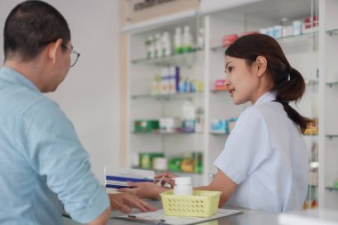 Medicine and health concept, Female pharmacist explains medicinal properties to client in drugstore.