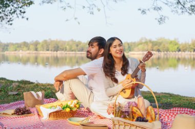 Birbirine aşık genç bir çift piknik yaparken sırt sırta oturup gitar çalıyorlar..