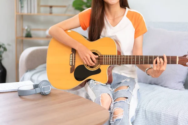 컨셉의 여성은 거실에서 어쿠스틱 기타로 음악을 연주하기 소파에 — 스톡 사진