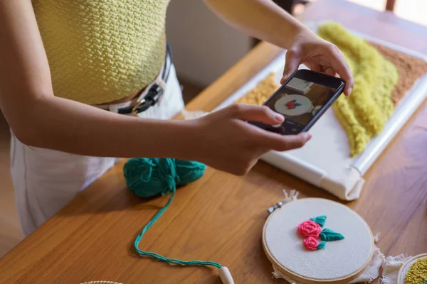 Hand embroidery concept, Women taking photo of embroidery fabric punch diy on canvas in wood hoop.