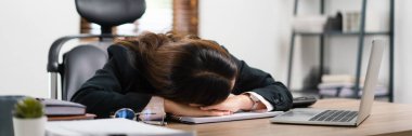 İş kadını iş yerinde aşırı çalışmaktan bitkin düştükten sonra dizüstü bilgisayarının yanında uyuyor..