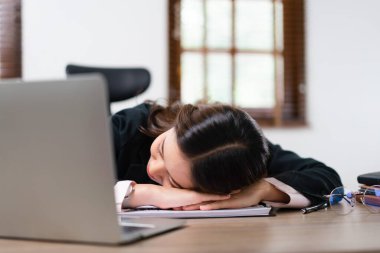 İş kadını iş yerinde aşırı çalışmaktan bitkin düştükten sonra dizüstü bilgisayarının yanında uyuyor..