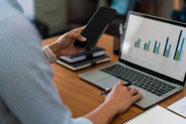 Ofiste dizüstü bilgisayarla çalışırken akıllı telefondan iş verilerini arayan iş kadınlarının kapatılması.