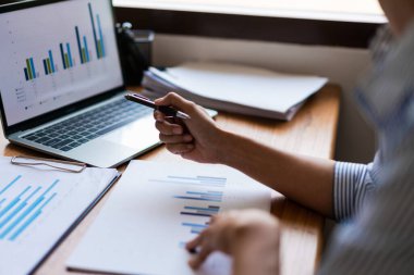 İşadamlarının elleri kapalı. Belgeleri okuyun ve finansal verileri ekranda kalemle gösterin..