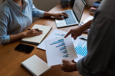 Finansal döküman grafiğine işaret eden işadamlarına ve dizüstü bilgisayarda yazan iş kadınlarına yakın dur..