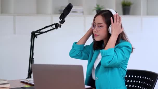 若いアジアの女性のプレゼンターやDjは オーディオポッドキャストを購読するか オーディオを作る マイクを使用して ヘッドフォンを身に着けている — ストック動画