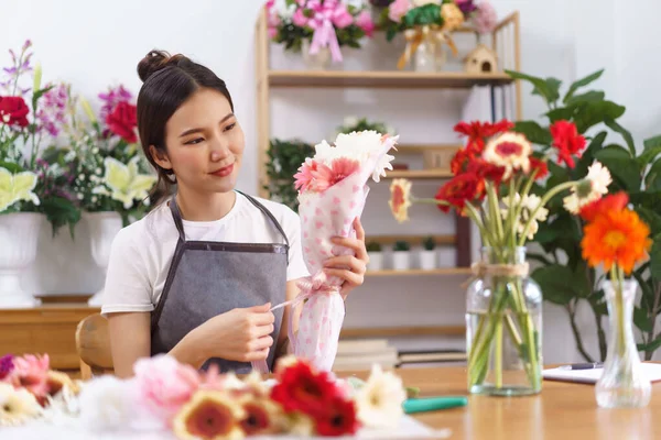 Florist concept, Female florist smile and holding colorful flower bouquet with paper and ribbon bow.