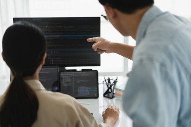 Web sitesini geliştirirken birden fazla monitörde kodları kontrol eden iki geliştirici.