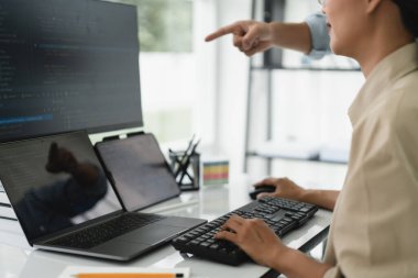 Web sitesini geliştirirken birden fazla monitörde kodları kontrol eden iki geliştirici.