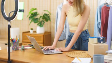 Çevrimiçi satış konsepti, moda tasarımcısı çevrimiçi kumaş alışverişini kontrol ediyor ve laptop üzerinde çalışıyor.