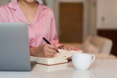 Kadın girişimci, iç işlerinde yeni strateji girişimi hakkında çalışırken not defterine veri yazar.
